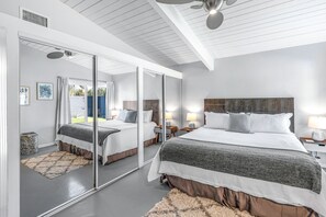 Un dormitorio moderno con una cama grande, un espejo y un ventilador de techo.