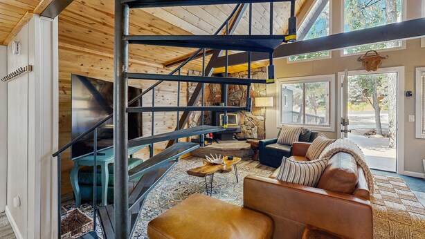 Amplia sala de estar con escalera, chimenea y un ventanal que ofrece vistas al exterior.