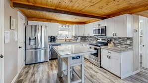 Una cocina moderna con vigas de madera en el techo, electrodomésticos de acero inoxidable y una isla central.