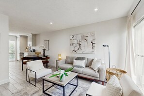 Ein modernes Wohnzimmer mit einer Couch, Sesseln, einem Couchtisch und einem Essbereich mit Tisch und Stühlen.