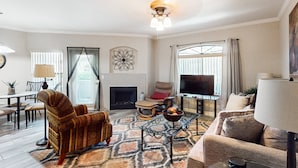 Una sala de estar con chimenea, televisión y un comedor con mesa y sillas.