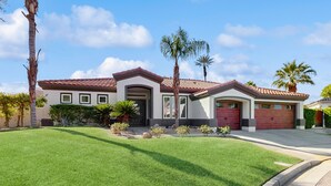 A two-story house with a red-tiled roof, a front entrance, and a well-maintained lawn.