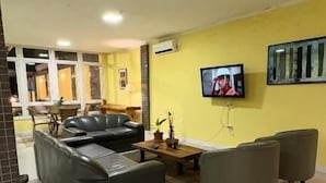 Una sala de estar con un sofá, sillones, una mesa de centro y un televisor instalado en la pared.