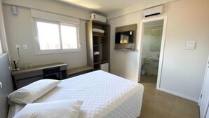 Un dormitorio con cama, escritorio, armario y televisor.