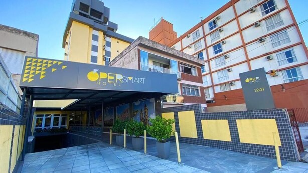 Exterior del HOTEL OPERSMART, con diseño moderno, que presenta una entrada cubierta y un camino de ladrillos.