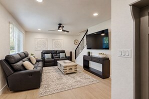 A modern living room with a sofa, coffee table, and a TV. - Modern Comfort & Desert Fun—A Chic Two-Story Home Base Minutes From Everything. (Scottsdale)