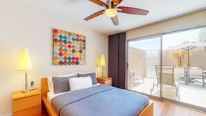 Ein modernes Schlafzimmer mit einem großen Bett, einem Deckenventilator und einem Balkon mit Gartenmöbeln.