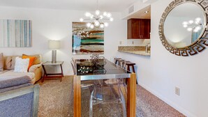 Ein modernes Wohnzimmer mit einem Glastisch, einer Couch, einem Couchtisch und einem großen abstrakten Gemälde.