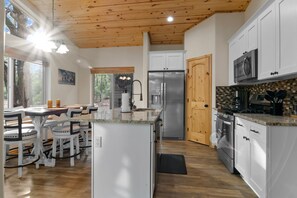 A modern kitchen with white cabinets, a stainless steel refrigerator, and a microwave. - Luxury home with patio, fireplace, BBQ grill, golf nearby (Show Low)