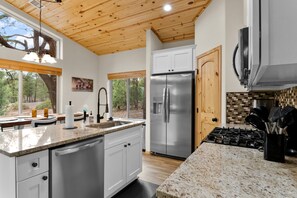 A modern kitchen with granite countertops, stainless steel appliances, and wooden ceiling beams. - Luxury home with patio, fireplace, BBQ grill, golf nearby (Show Low)
