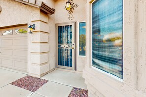 Una casa con puerta de garaje, un aplique decorativo en la pared y un gran ventanal con panel de vidrio texturizado.