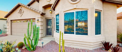 A house with a garage, large windows, and cacti in the front yard.
