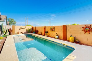 Une piscine avec un mur en briques, des éléments décoratifs muraux et des plantes en pot.