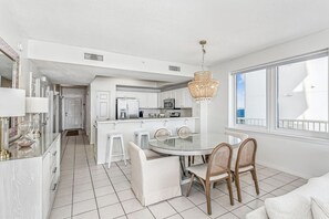 Une cuisine moderne avec des meubles blancs, un îlot central doté de tabourets et un lustre.