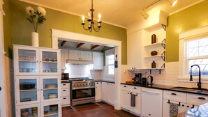 A kitchen with white cabinets, a stove, and a sink. - Hot Tub in Downtown Blue Beauty - Walk to Lake, Sherman & Events (Coeur d`Alene)