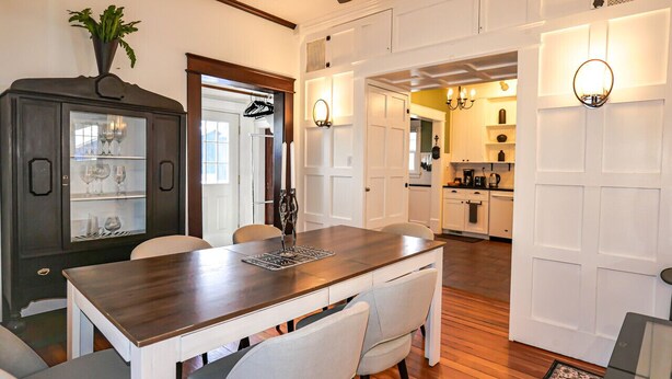 A dining area with a wooden table and chairs, a ceiling fan, and a dark wooden cabinet with glass doors. - Hot Tub in Downtown Blue Beauty - Walk to Lake, Sherman & Events (Coeur d`Alene)