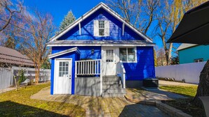 A blue house with a front porch, a small garage, and a brick pathway leading to the entrance. - Hot Tub in Downtown Blue Beauty - Walk to Lake, Sherman & Events (Coeur d`Alene)