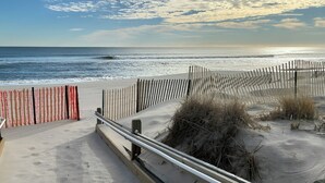 Une plage bordée d’une clôture en bois et d’une rambarde en métal.