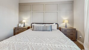 Ein Schlafzimmer mit einem Bett, zwei Nachttischen und einem Kopfteil.