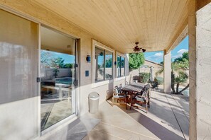 Ein überdachter Patio-Bereich mit Holzboden, einem Tisch mit Stühlen und Blick auf die umliegende Landschaft.
