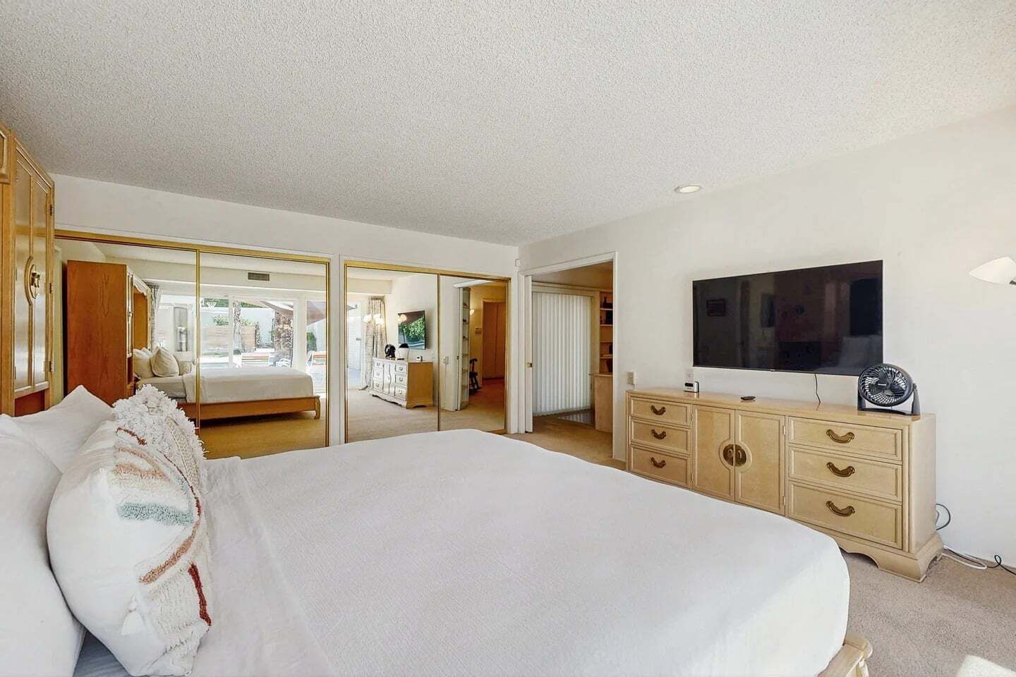 Une chambre d’hôtel avec un grand lit, une télévision, une commode et un miroir.