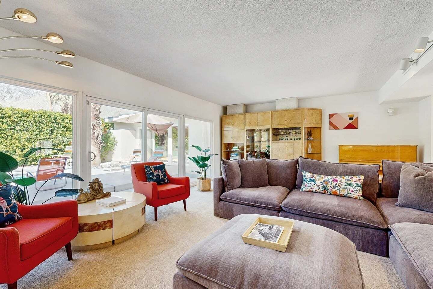 A modern living room with a sofa, armchairs, a coffee table, and a bookshelf.