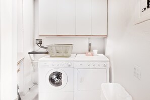 A laundry area with two washing machines, a basket, and a soap dispenser. - Stylish Dog-Friendly Retreat W/ High-Speed WiFi, Pool & Spa, & Pool Table (Palm Springs)