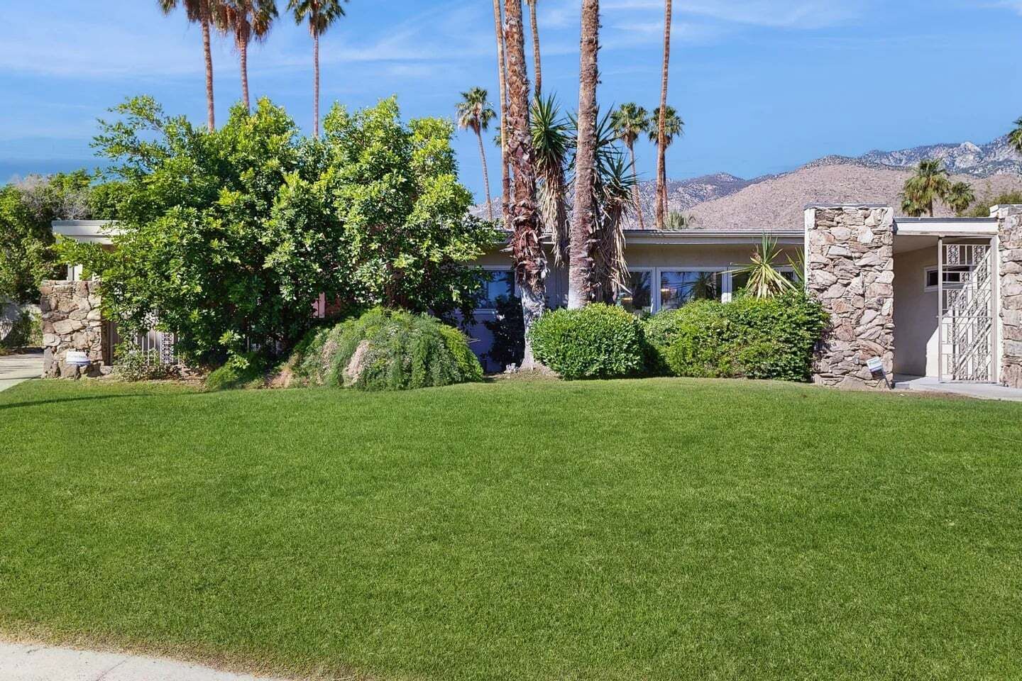 Un immobile residenziale con un prato curato, un ingresso in pietra e vista sulle colline circostanti.