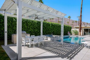 A covered outdoor area with a pool, white furniture, and a grill. - Stylish Dog-Friendly Retreat W/ High-Speed WiFi, Pool & Spa, & Pool Table (Palm Springs)