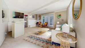 Uma sala de estar moderna com um sofá, uma mesa de centro e um espaço de jantar com uma mesa e cadeiras brancas.