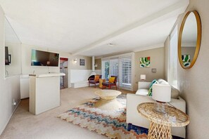 A modern living room with a sofa, a coffee table, and a dining area with a white table and chairs. - Stylish Dog-Friendly Retreat W/ High-Speed WiFi, Pool & Spa, & Pool Table (Palm Springs)