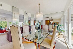 A modern dining area with a glass table, upholstered chairs, and a chandelier. - Stylish Dog-Friendly Retreat W/ High-Speed WiFi, Pool & Spa, & Pool Table (Palm Springs)