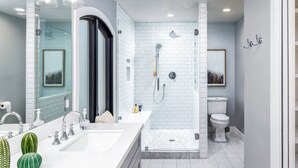 Een moderne badkamer met een grote spiegel, een wit wastafelmeubel en een inloopdouche.