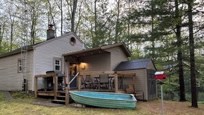 A house with a boat docked outside, a porch with chairs, and a mailbox. - Rocky Top Cabin Higgins Lake, cozy hillside retreat walking distance to the lake (Roscommon)