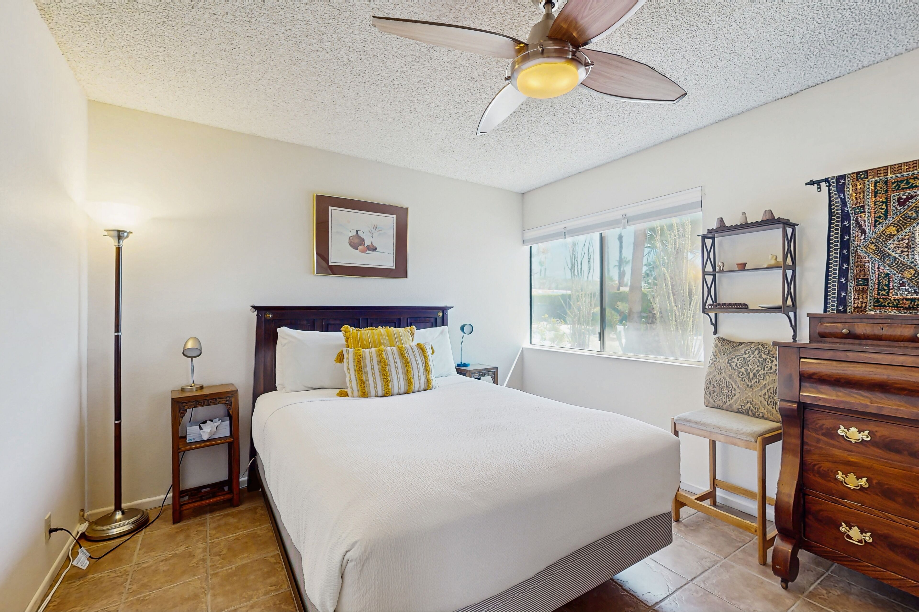 A neatly arranged bedroom with a bed, bedside table, lamp, and a ceiling fan.