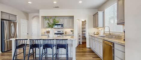 A modern kitchen with a central island, white cabinetry, and a stainless steel refrigerator.
