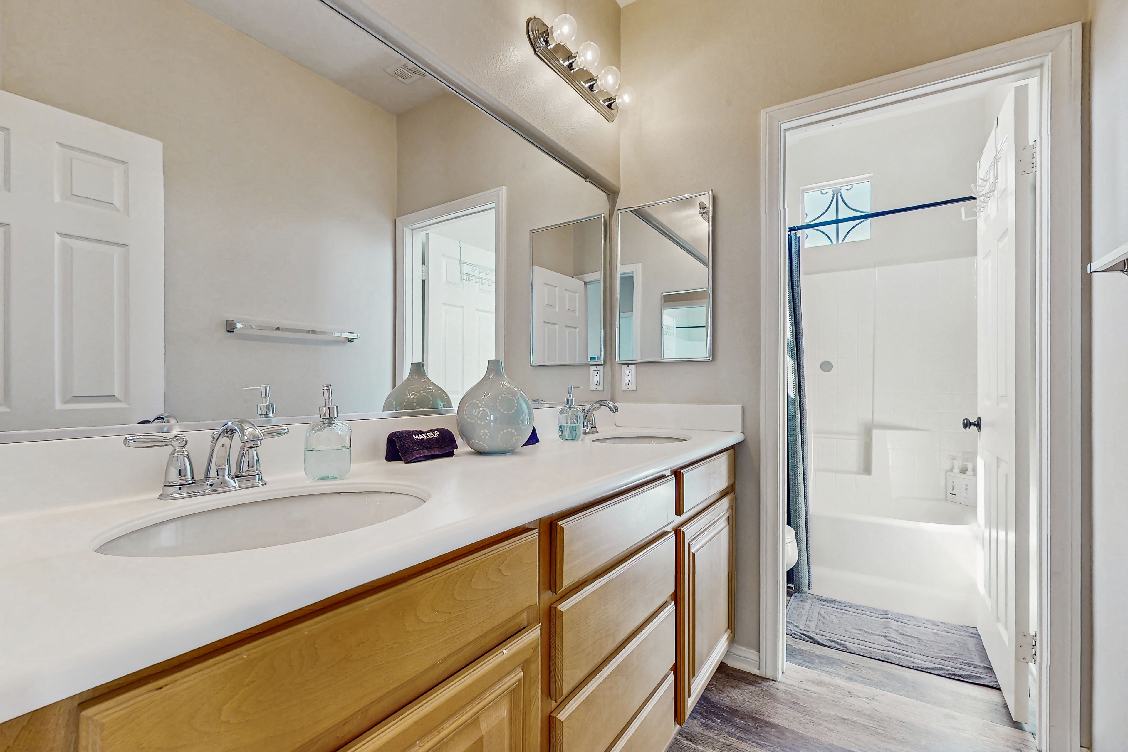 A bathroom with two sinks, a mirror, and a shower area.