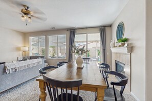 A dining area with a wooden table, chairs, a sofa, and a fireplace. - Stunning Terra Lago Home w/Pvt. Grill, Pool & Spa+Next to Terra Lago Golf Course (Indio)