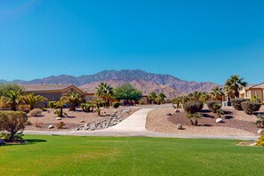 A residential area with houses, a paved driveway, and a mountain backdrop. - Modern, Dog-Friendly Condo on Golf Course-Steps to Pool & Hot Tub + Tennis & Spa (Cathedral City)