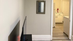 Ein Flur mit Fernseher, Spiegel und einer Tür zum Küchenbereich.