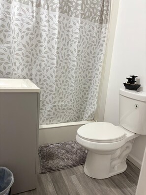Ein Badezimmer mit Toilette, Waschbecken und einer Duschkabine mit Blättermuster.
