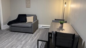 Ein modernes Wohnzimmer mit einem grauen Sofa, einem Holzesstisch und einer Stehlampe.