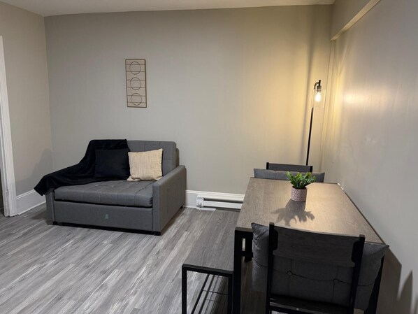 A modern living room with a grey sofa, a wooden dining table, and a floor lamp. - Welcoming 1-bedroom apartment in charming Ashland perfect for getaway (Ashland)