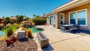 Patio con piscina, mobili da esterno e un elemento decorativo a forma di focolare in pietra.