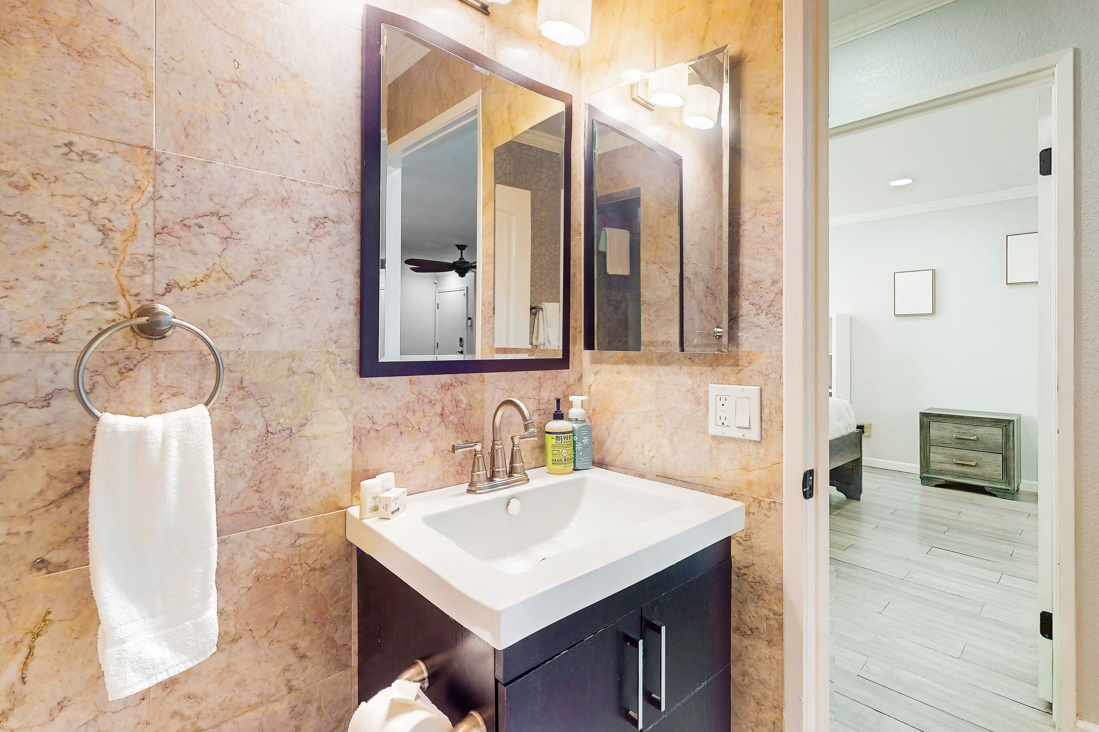 Un bagno con un lavandino bianco, uno specchio grande e un portasciugamani.