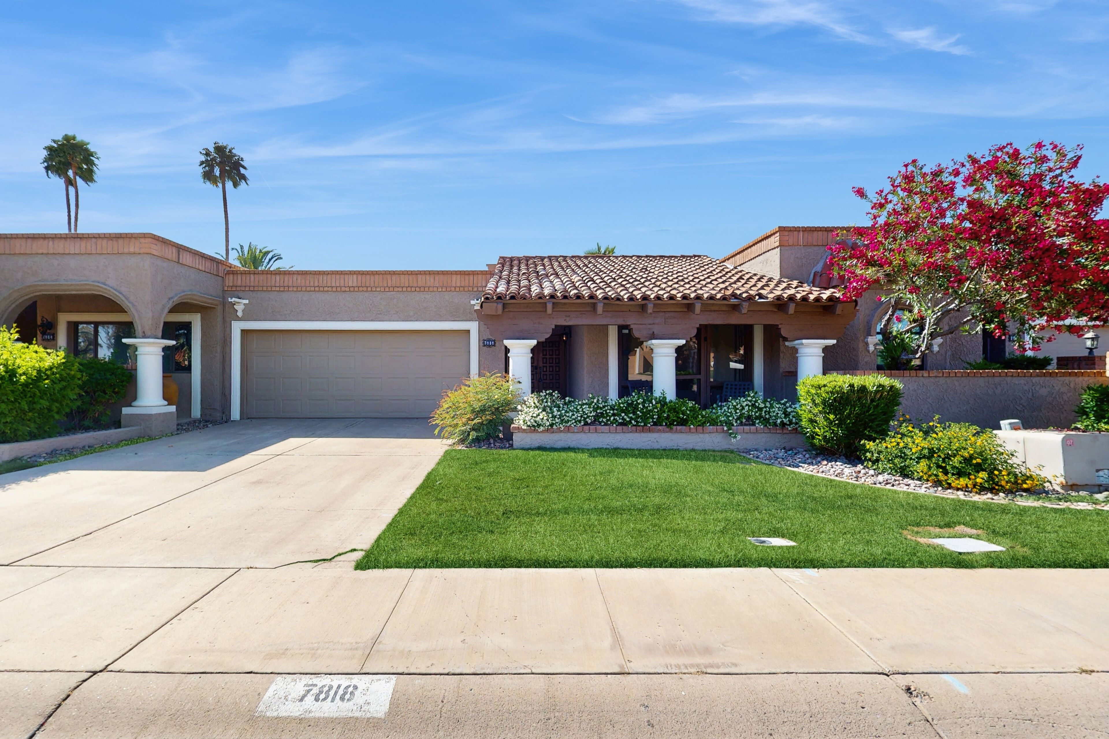 A residential house with a garage, a well-maintained lawn, and a clear sky.