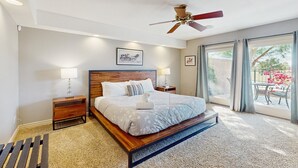 Een moderne slaapkamer met een houten bed, een plafondventilator en een groot raam met gordijnen.