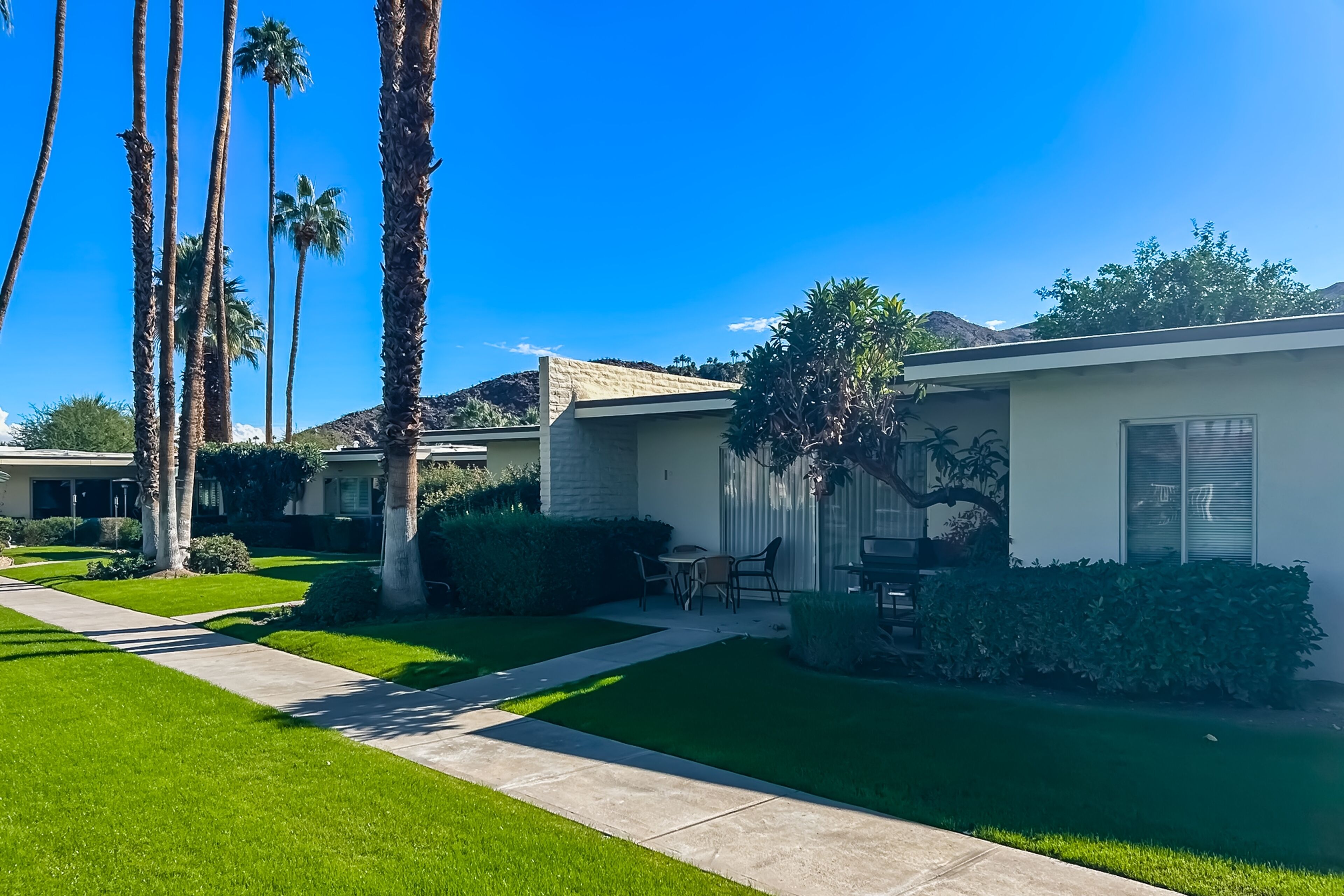 A residential area with houses, palm trees, and a clear blue sky.