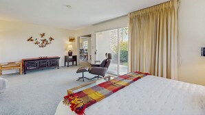 A hotel room with a large bed, a desk, a chair, and a view of the outdoors. - Sunny Palm Springs Retreat with Shared Pool, Hot Tub & Prime Location! (Palm Springs)
