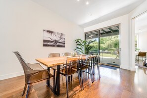 Ein moderner Essbereich mit einem Holztisch, klaren Kunststoffstühlen, einem großen Fenster und einer Tür, die auf eine Terrasse führt.
